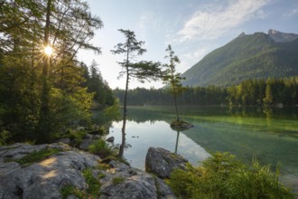 Summer morning at Hintersee near Ramsau in Berchtesgadener Land with sun star and reflection. The