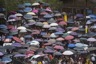 People attend holding umbrellas at an event organised to mark the Behdienkhlam festival in Jowai,