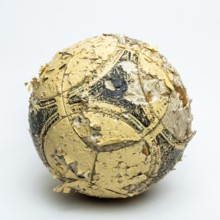 A worn football ball rests against a neutral background, displaying significant peeling and faded