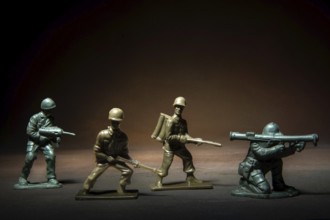 Four miniature soldier figures positioned in a tense standoff, showcasing various combat stances