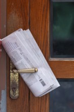 Fresh newspaper waiting at the door in the early morning. Newspaper on the door handle