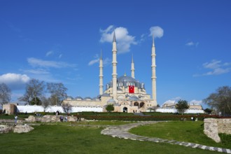 Mosque with dominant minarets and a spacious garden in front of it. Clear day with blue sky.