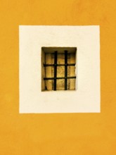 A small rectangular window with a black barred grille is centered in a white square, surrounded by