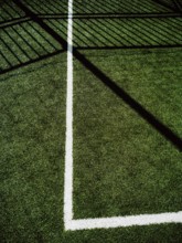 This corner of a sports field features vibrant artificial turf with clear white lines marking the
