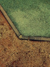 This detailed view captures the unique transition of a playground surface from vibrant green rubber