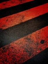 A vibrant red and black striped crosswalk painted across the asphalt. The surface shows signs of