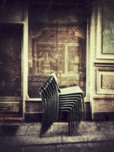Stacked chairs lean against an inviting building exterior, capturing the peaceful ambiance of a