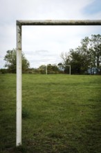 Football goalpost in a grassy field under a cloudy sky near a rural area. Auvergne. France