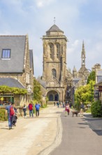 Tourists on city street in the old town of Locronan with the church a sunny summer day, Locronan,