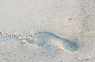 A single footprint in the sand on the beach, quiet atmosphere, warm light in the evening, human