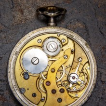 A detailed close up of a vintage pocket watch reveals its delicate gears and mechanisms. This