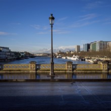 A street light stands tall on a bridge, casting light on the path as the serene Seine River flows