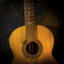 This classical guitar, resting against a dark brown backdrop, features broken strings that