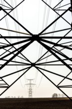 A high voltage electricity post stands prominently in an expansive field in Auvergne Rhone Alpes,
