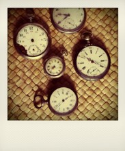 Various vintage stopwatches are displayed closely on a woven surface, highlighting their distinct