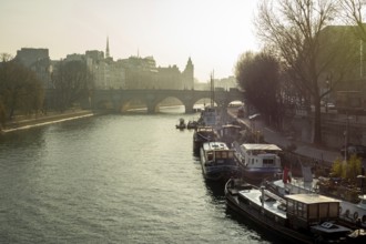 Barges float calmly on the river Seine, surrounded by historic Parisian architecture under soft
