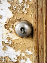Close view of a keyhole on a weathered, peeling door demonstrates intricate details and textures.