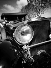 This vintage car displays its polished headlight and elegant grille. The scene captures the beauty
