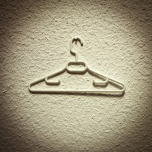 A clothes hanger is displayed prominently against a textured wall, showcasing its sleek design and