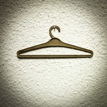 A clothes hanger is suspended from a textured wall, showcasing a minimalist design. The simple