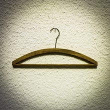 Wooden hangers are displayed against a textured light wall, highlighting a minimalist approach to