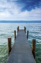 A sturdy jetty extends into the serene waters of Lake Geneva, surrounded by mesmerizing blue hues