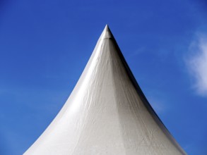 The white circus tent rises prominently against a backdrop of a cloudy sky, showcasing its sharp
