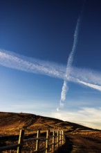 A rustic stretch of barbed wire fencing runs along a pathway in the Regional Nature Park of Volcans