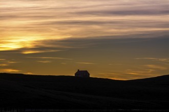 A tranquil farm stands silhouetted against the colorful sky at sunset, showcasing the natural