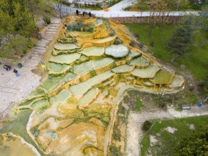 Multicoloured natural mineral terraces with water accumulations in a park landscape, aerial view,