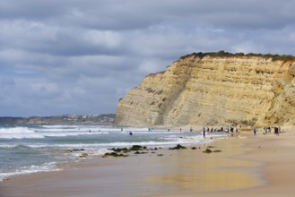 Surfers on the beach and cliffs, Praia de Porto de Mos, Algarve, Portugal