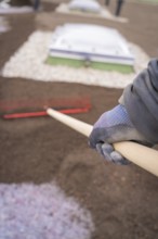 Close-up of a worker working the soil on a roof with a rake, roof greening, house construction,