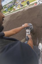 Close-up of a worker using a tool on a floor, roof greening, house construction, climate neutral