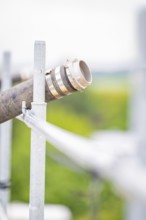 Metal pipe with mounting in blurred, green background, roof greening, house construction, climate
