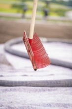 A free-floating red rake in front of a roof with a blurred background in a construction site