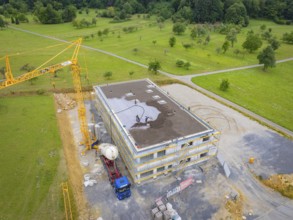 Drone view of a construction site with construction workers, crane and vehicles on a green area,