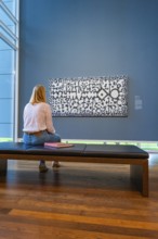 Woman sitting on a bench and looking at a work of art on a blue wall, Frieder Burda Museum, Baden