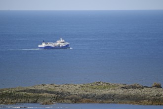 A large fishing vessel navigates the blue sea along the rocky coastline, Sumburgh Head, Shetland