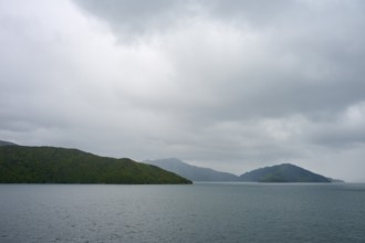 View of calm sea with cloudy sky and green islands, summer, Cook Strait, North Island, South