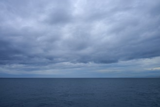 The sea stretches as far as the horizon under a cloudy sky, summer, Cook Strait, North Island,