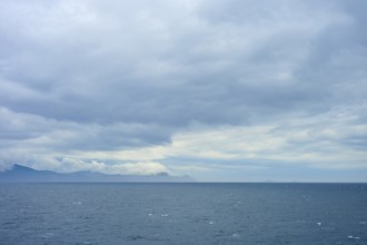 Wide sea with cloudy sky and distant mountains on the horizon, summer, Cook Strait, North Island,