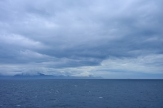 Sweeping views of the sea and distant clouds over the mountains on the horizon, summer, Cook