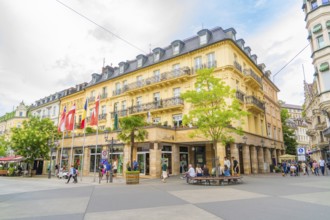 Corner building with balconies and flags, lively with people, urban atmosphere, Baden Baden,