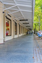 Strollers under arcades with shops, surrounded by trees and urban flair, Baden Baden, Germany