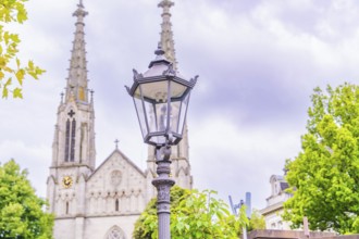 A classic street lamp stands in the foreground, behind it the towers of an impressive Gothic