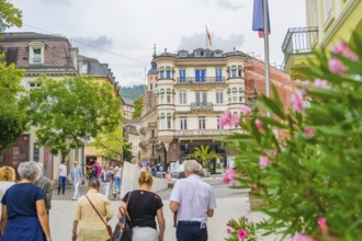 Lively street scene with people, surrounded by historic buildings and flowering plants, Baden