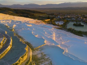 Panorama of terraces and water with mountain backdrop in the soft light of dusk, aerial view,