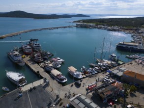 Sunny harbour with boats and yachts, surrounded by azure blue water and landscape, aerial view,