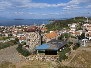 Coastal panorama with striking windmill, surrounded by houses and hills, aerial view, Alibey,