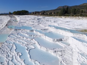 Extensive limestone sinter terraces with water and surrounding landscape in Pamukkale, aerial view,